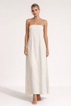 Strapless beige maxi jurk in minimalistisch design gedragen met kleine handtas