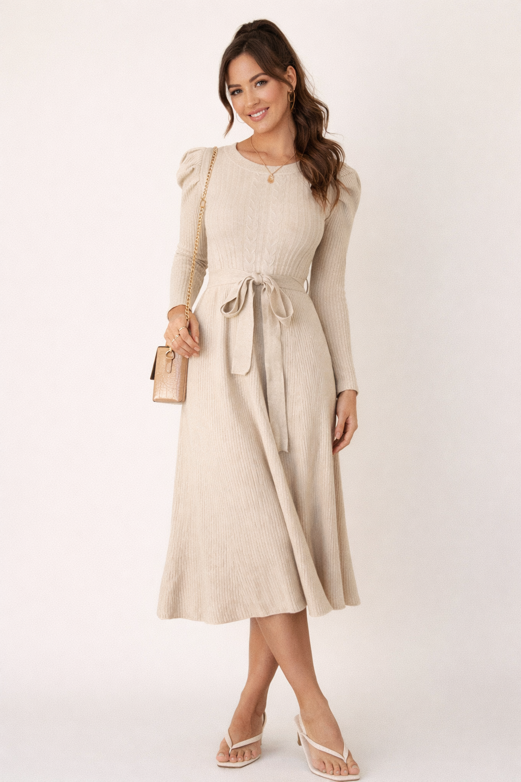 Beige gebreide midi jurk met ceintuur gedragen door model in elegante setting