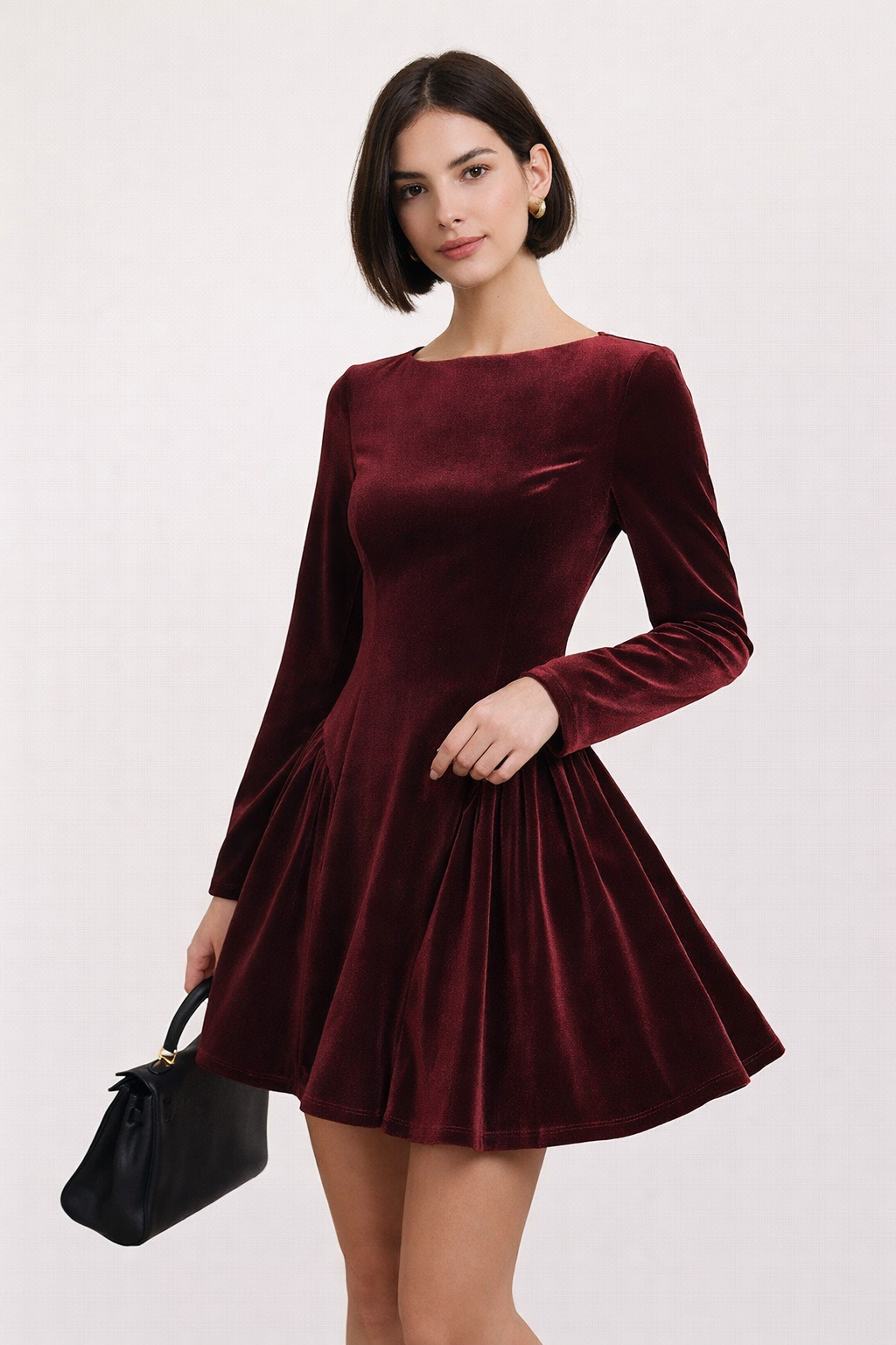 Bordeauxrode fluwelen mini jurk met lange mouwen en geplooide rok gedragen door vrouw in elegante setting