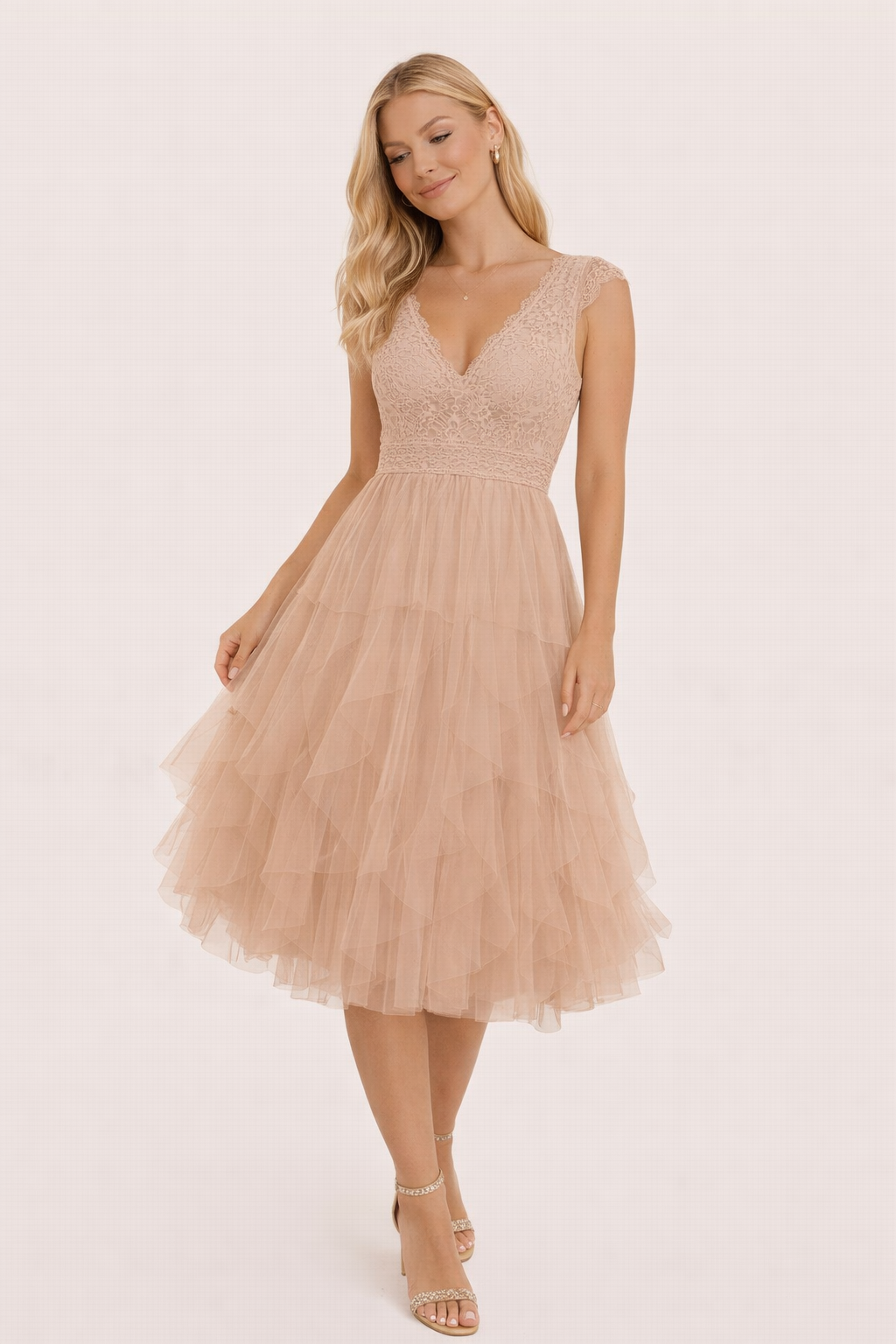 Vrouw draagt elegante nude tule midi jurk met kanten top en gelaagde rok tijdens luxe buiten setting