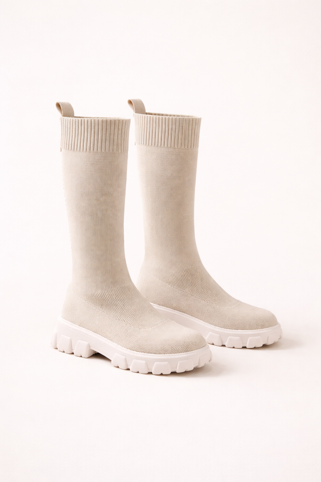Beige knit combat boots met chunky witte zool gedragen door een vrouw, moderne soklaarsstijl met comfortabele pasvorm.