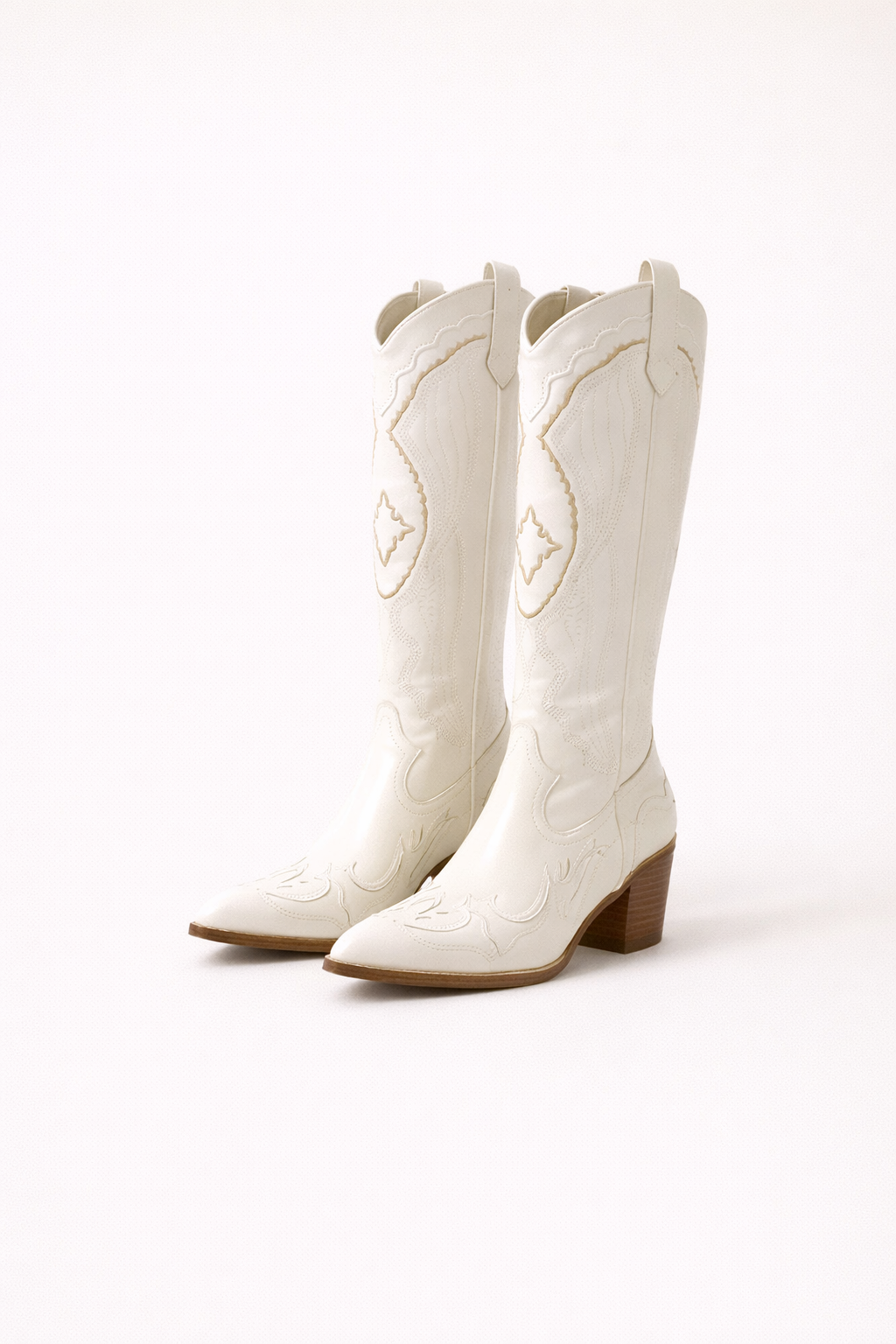 Witte western laarzen met sierlijke stiksels en puntige neus gedragen door een vrouw in een moderne interieursetting.